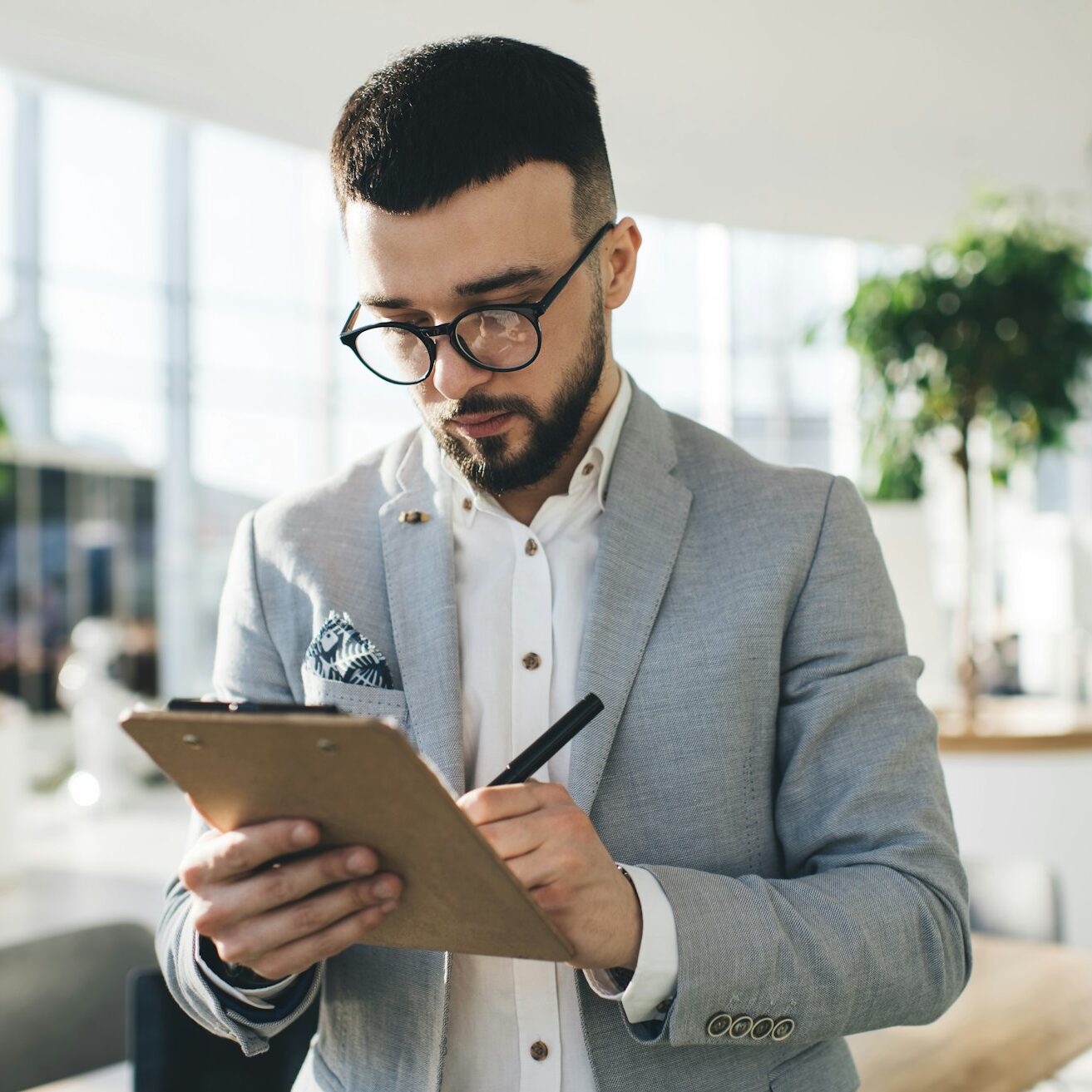 Focused businessman writing on clipboard