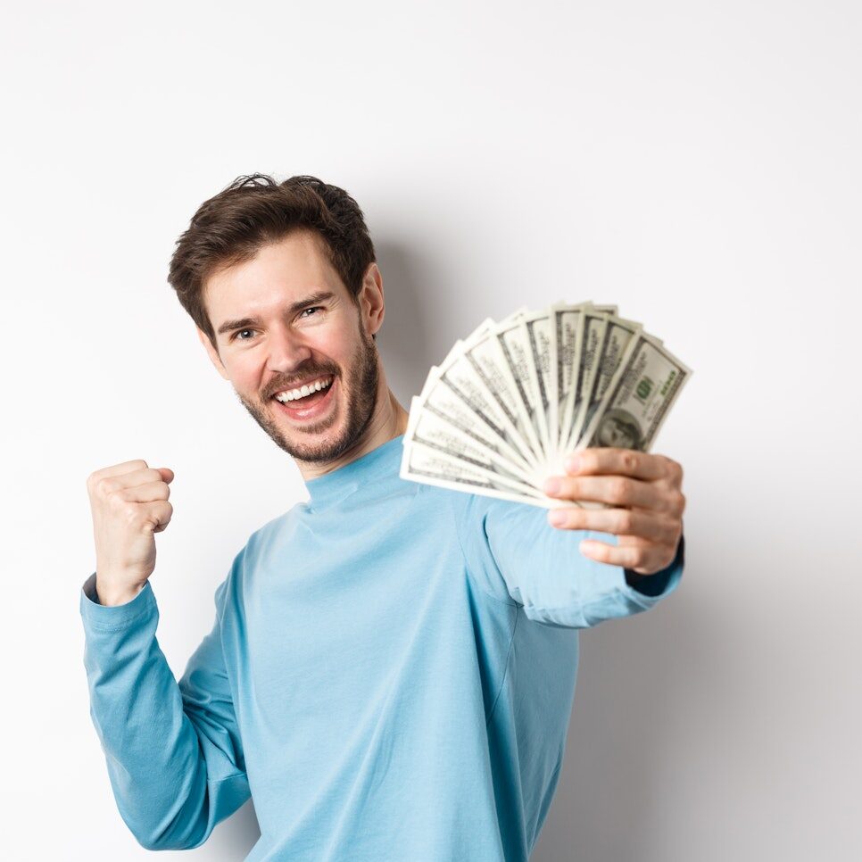 Happy caucasian man stretch out hand with money in dollars, saying yes and celebrating income, got