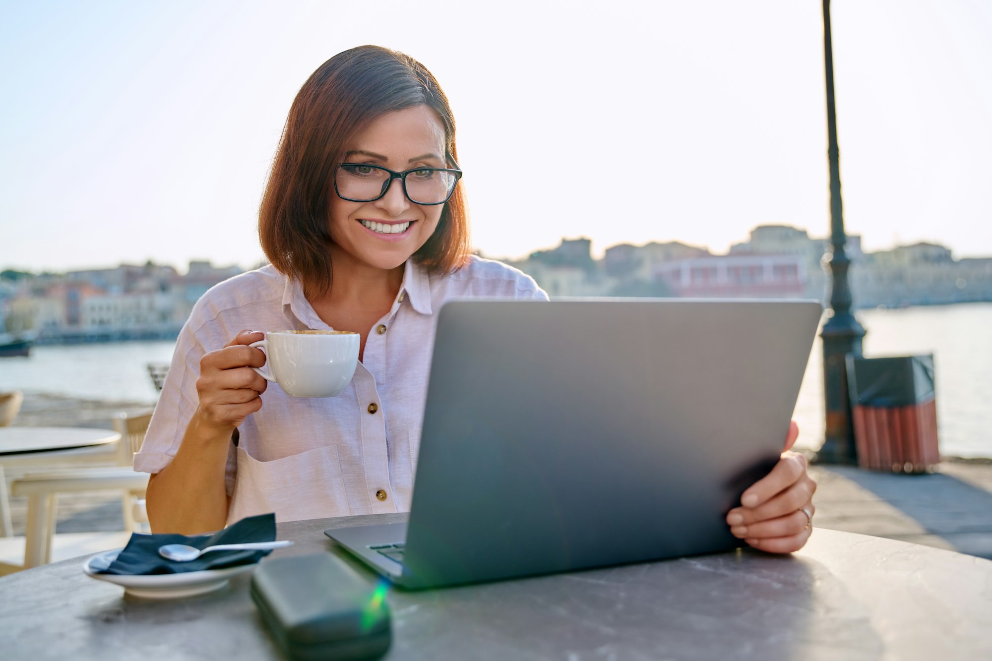 Smiling middle aged business woman in cafe with laptop