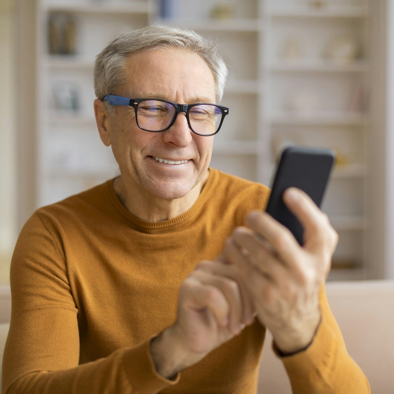 Smiling senior with glasses looking at phone